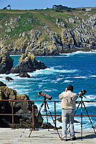 Birdwatcher with telescopes scanning the cliffs at Cap de Sizun, nature reserve and bird sanctuary in Finistère, Brittany, France June 2011