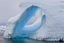 A large hole in an iceberg with icicles hanging. Yalour Islands, Antarctic Peninsula, Antarctica, December.
