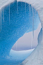 A large hole in an iceberg with icicles hanging. Yalour Islands, Antarctic Peninsula, Antarctica, December.