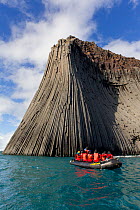 Columnar basalt formations at the 180 metre high Edinburgh Hill. Zodiac full of cruise ship tourists for scale. South Shetland Islands, Antarctica, December.