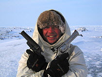 Cameraman Doug Allan holding pistols, used to scare off Polar bears. Kong Karl's Land, Svalbard, April. Freeze frame book plate page 19.