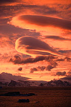 Orange lenticular clouds above mountainous landscape. South Orkney Islands, Antarctica. Freeze Frame book plate page 65.
