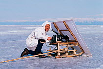 Cameraman Doug Allan filming seals with white sail for camouflage, Lake Baikal, Siberia, Russia, April 1989. Freeze Frame book plate page, 48.