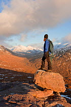 Woman standing on rock admiring the view on the descent from Tom na Gruagaich, Beinn Alligin, Torridon, Scotland, UK, February 2010 Model Released