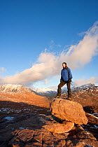 Woman standing on rock admiring the view on the descent from Tom na Gruagaich, Beinn Alligin, Torridon, Scotland, UK, February 2010 Model Released