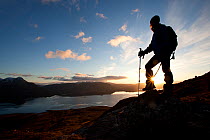 Walker silhouetted at sunset looking out over Loch Torridon, Beinn Alligin, Torridon, Scotland, UK, February 2010 Model Released