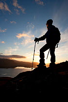 Walker silhouetted at sunset looking out over Loch Torridon, Beinn Alligin, Torridon, Scotland, UK, February 2010 Model Released