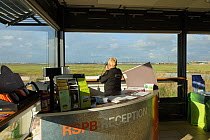 Receptionist watching birds from inside the Visitor Centre, Rainham Marshes RSPB Reserve, RSPB Greater Thames Futurescapes Project, Rainham, Essex, UK, November 2011