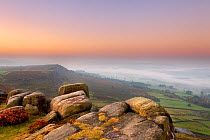 Scenic view from Curbar Edge at dawn, with mist in the distance and rock formations in the foreground, Peak District NP, UK, September 2011