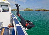 Underwater photographer Alex Mustard diving off the side of Sea Life Surveys boat Sula Crion at the Cairns of Coll, Inner Hebrides, Scotland, UK, July 2011