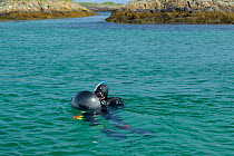 Underwater photographer Alex Mustard in the water with camera and dome port at the Cairns of Coll, Inner Hebrides, Scotland, UK, July 2011