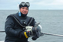 Portrait of underwater photographer Alex Mustard wearing a wetsuit with camera and dome port, Inner Hebrides, Scotland, UK, July 2011