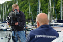 Film-maker Raymond Besant filming an interview with Sea Life Surveys founder and proprietor Richard Fairbairns on board Sula Beag, a dedicated wildlife watching boat in Tobermory harbour, Isle of Mull...