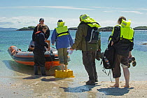 Sea Life Surveys wildlife watching tourists wearing life jackets boarding an inflatable boat, leaving the Cairns of Coll, Inner Hebrides, Scotland, UK, July 2011