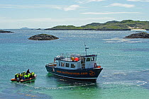 Sea Life Surveys passengers leaving the Cairns of Coll in an inflatable boat, heading towards the Sula Beag, a dedicated wildlife watching boat, Inner Hebrides, Scotland, UK, July 2011