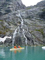 Kayakers near a waterfall, Margerie Glacier, Glacier Bay National Park, Alaska, USA, May 2011