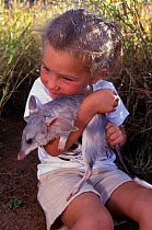 Girl cuddling a Bilby (Macrotis lagotis) at the Conservation Commission, Alice Springs, Northern Territory, Australia, May 1995, captive, vulnerable species