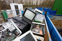 Computer monitors and television sets in containers at a recycling centre, Stroud, Gloucestershire, UK, February 2008.
