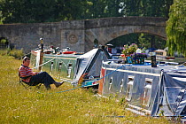 Man relaxing on chair next to his barge, River Thames at Lechlade, Gloucestershire, July 2008.