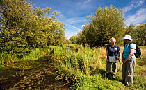 Two walkers next to a river, Cotswold Wardens Walk, Area of Outstanding Natural Beauty (AONB) at Eastleach Turville, Gloucestershire, UK, July 2008.