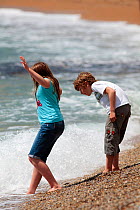 Children playing in sea on Durdle Door Beach, Dorset, UK, May 2009.