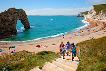 Family walking up steps from Durdle Door Beach onto the South West Coast Path National Trail, Dorset, UK, May 2009.