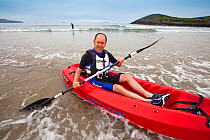 Man sea kayaking at Caerfai Bay on the Pembrokeshire Coast Path, Wales, UK, June 2009.
