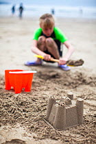 Child building a sand castle at Caerfai Bay on the Pembrokeshire Coast Path, Wales, June 2009.