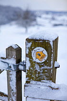Cotswold Way National Trail waymarker information sign and gate covered in snow, Coaly Peak, Gloucestershire, UK, January 2010.