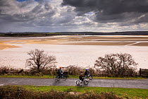 Two cyclists on The Tarka Trail cycle path on a dark cloudy day, Devon, UK, March 2010.