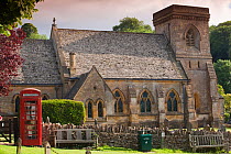 Church with traditional red telephone box outside and dry stone wall, Snowshill, Cotswolds, UK, June 2011.