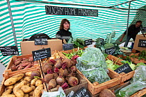 Woman selling fresh vegetable produce at Cirencester Farmers Market, Cirencester, Gloucestershire, UK, July 2011.