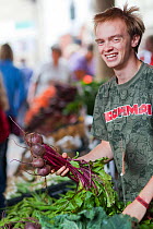 Man smiling holding beetroot at Stroud Farmers Market, Stroud, Gloucestershire, UK, August 2011.