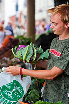 Man putting vegetables in bag at Stroud Farmers Market, Stroud, Gloucestershire, UK, August 2011.