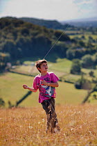 Boy kite flying on Selsley Common (unimproved grassland) Stroud, Gloucestershire, UK, August 2011. Model released