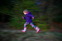 Young girl running along the edge of woodland, Norfolk, UK, January 2012 Model released