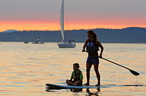 Woman paddleboarding with child in the waters of Puget Sound, Seattle, Washington, USA