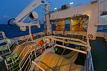 Crew working at dusk on deck of the pelagic trawler 'Charisma', Shetland Isles, Scotland, UK, October 2011, Model Release available