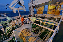 Crew working on deck of the pelagic trawler 'Charisma' at dusk, showing trawler nets and winches, Shetland Isles, Scotland, UK, October 2011