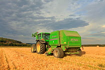 Baling machine collecting Barley (Hordeum vulgare) straw on arable farmland, Scotland, UK, September