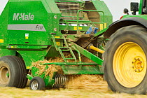 Baling machine collecting Barley straw on arable farmland, Scotland, UK, September