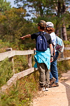 Children looking for wildlife and pointing from the edge of a track, Arne RSPB reserve, Dorset, England, UK, September. Model released.