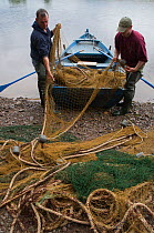 Derek Purvis (left) and another boatman preparing a boat and nets for a 'run' on the River Tweed, casting the net to catch migratory Atlantic salmon (Salmo salar) and Sea trout (Salmo trutta) for moni...