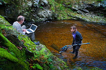 2020VISION photographer Linda Pitkin working with her husband Brian Pitkin photographing Brown trout (Salmo trutta) and Atlantic salmon (Salmo salar) with an underwater polecam, River Tweed, Cheviot H...