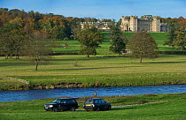 View of Floors Castle over the River Tweed, with fishermen and cars in the foreground, near Kelso, Roxburghshire, Scotland, UK, October 2010