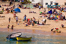 Holiday makers on the beach in the sun, St. Ives Harbour, Cornwall, England, UK, June 2011