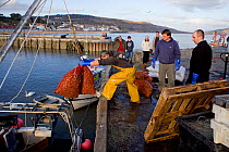 Fishermen unloading bags of Common whelks (Buccinum undatum) at the harbour (The Cobb), Lyme Regis, England, UK, February 2011