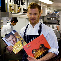 Tom Aikens, owner of Tom Aikens Restaurant, holding a copy of his Fish recipe book and a 2020VISION promotional book, Tom is a vocal supporter of sustainable fishing practices, Chelsea, London, Englan...