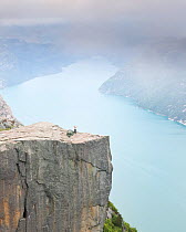 Person stretching after waking up on the Pulpit Rock, 604 meters above the Lysefjorden, Rogaland, Norway, Scandinavia, Model released