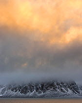 Mountain tops in clouds at sunset over Raudefjorden, Northern Spitsbergen, Svalbard, Norway, September